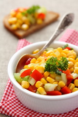 Homemade corn salsa in white bowl with spoon