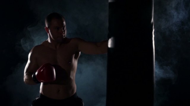 Boxer training shadow boxing over black background. Slow motion.