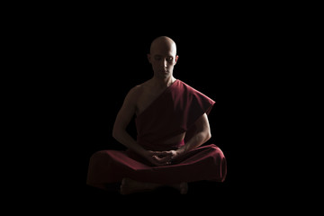 buddhist monk in meditation pose over black background