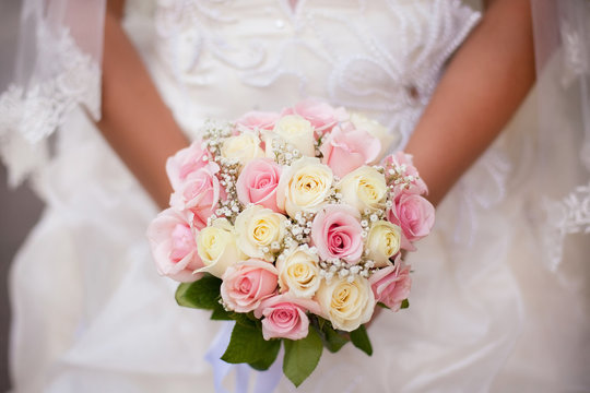 White and pink wedding bouquet with roses in bride's hands