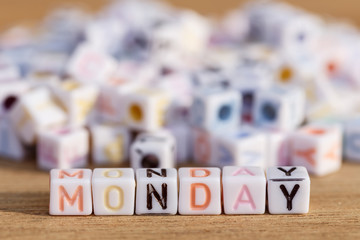 Monday written in letter beads on wood background