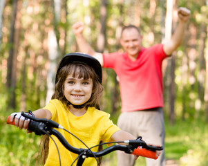 Obraz premium happy father rejoices that her daughter learned to ride a bike