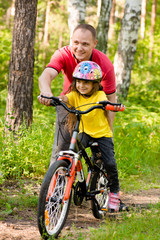 Fototapeta na wymiar father teaching his daughter to ride a bike