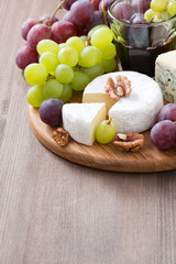 assorted soft cheeses and fresh grapes on wooden background