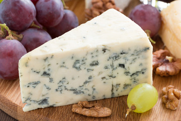 blue cheese on a wooden board and fresh grapes