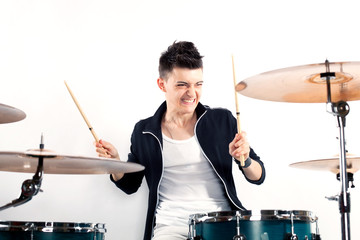 Fototapeta premium Expressive young drummer playing at the drums with drum stick