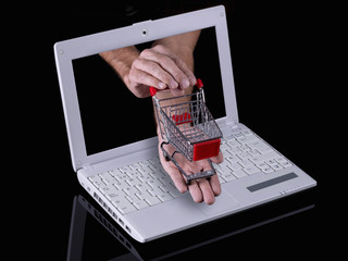 Hand reaches out of a laptop with a shopping cart