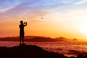 man taking photos of sunset with mobile phone