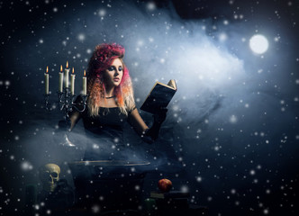 Beautiful witch making witchcraft on a snowy background