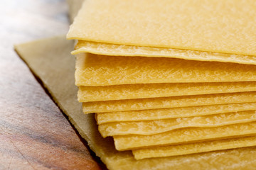 Uncooced lasagne pasta sheets on wooden table