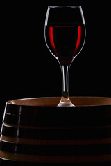 Glass of wine over a barrel. Wine culture