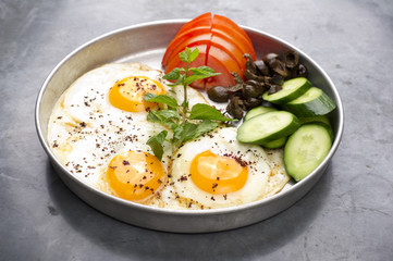 Fired eggs presentation with mints, tomato, olive and cucumber