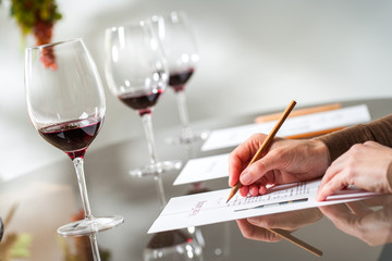 Hands taking notes at wine tasting.