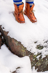 Female with leather boots standing in the snow on top of the roc