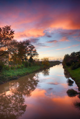Fototapeta na wymiar Wonderful sunset colors of fall with river reflections