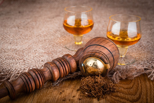 Vintage brown  pipe with brandy on wooden background