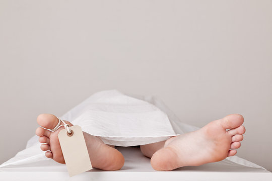 Covered Dead Body In The Morgue With A Tag Attached To The Toe