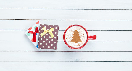Fototapeta na wymiar Gift box and cappuccino on white wooden table.