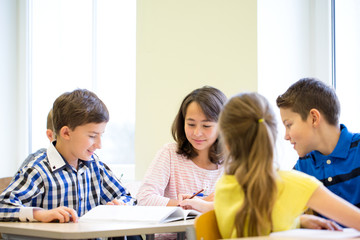 group of school kids writing test in classroom