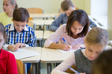 group of school kids writing test in classroom