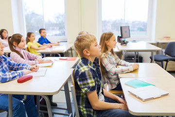 group of school kids with notebooks in classroom
