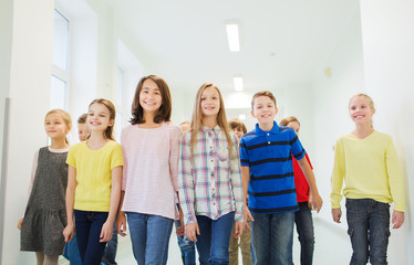 group of smiling school kids walking in corridor
