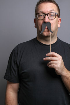 Mann mit Papierschnurrbart und d&auml;mlichem Gesichtsausdruck