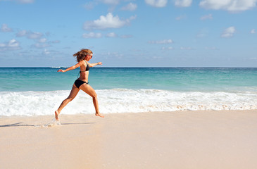 Happy woman running on the beach.