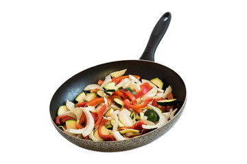 frying pan with vegetables on white