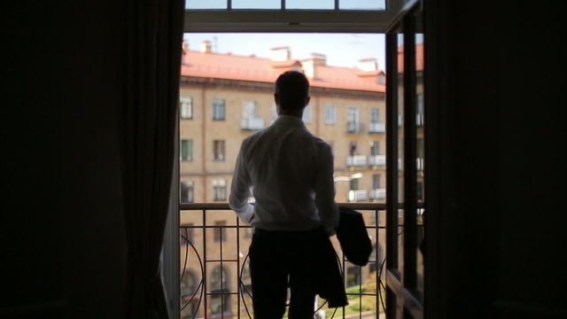 Silhouette of a man wears a jacket standing on the balcony