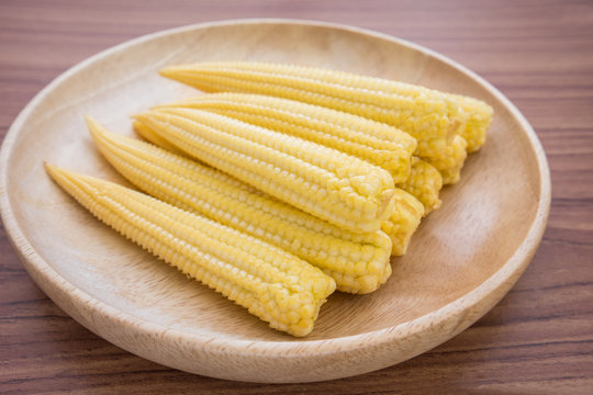 Fresh baby corn on wooden plate