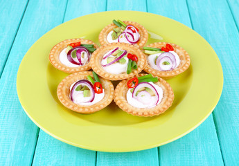 Tartlets with greens and vegetables with sauce on plate on