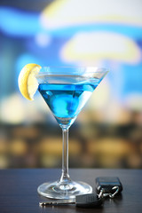 Glass of alcoholic drink and car key,