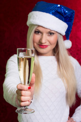 Girl in santa hat in white sweater smiling with a glass of champ