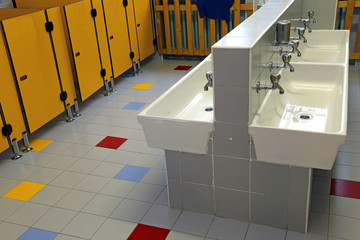 bathroom of a nursery with white sinks and toilet doors