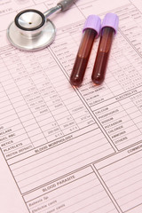 Blood test tube and  stethoscope on pink background.