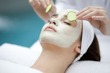 Beautiful young woman receiving facial mask of cucumber in beaut - 74063646