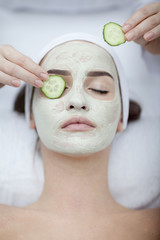 Beautiful young woman receiving facial mask of cucumber in beaut - 74063693