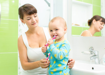 Obraz na płótnie Canvas mother with child girl brushing teeth