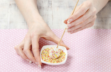 Woman decorating cake pops with colorful sprinkles