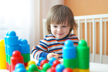 Fototapeta na wymiar toddler boy plays plastic blocks