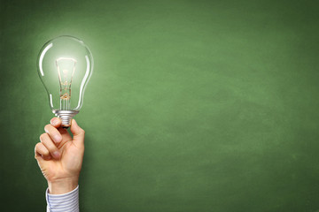 Hand mit Lampe vor einer Tafel