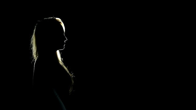 Silhouette of a woman who prays in the moonlight