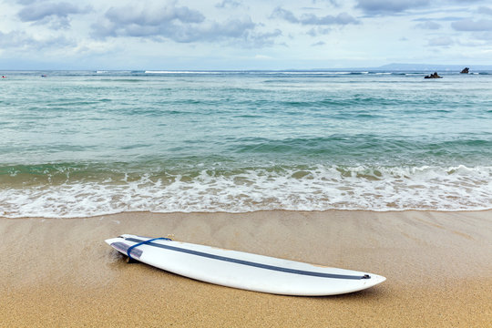 Surfboard lying on sand near the ocean