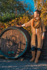 Full length portrait of thoughtful woman near wooden barrel