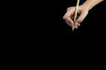 Hand holding wooden pencil isolated on black background