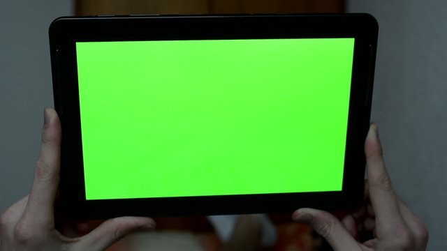 Man lies in bed and holds a tablet - green screen