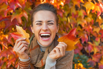 Portrait of happy young woman with leafs in front of foliage