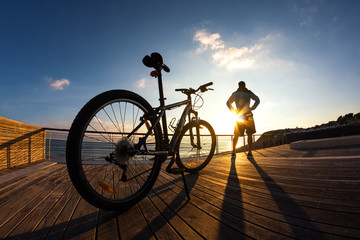 silhouette of sportsman and mountain bike at sunset