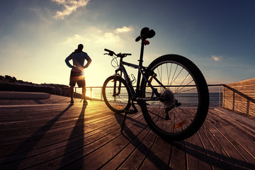 Fototapeta na wymiar silhouette of sportsman and mountain bike at the sunset